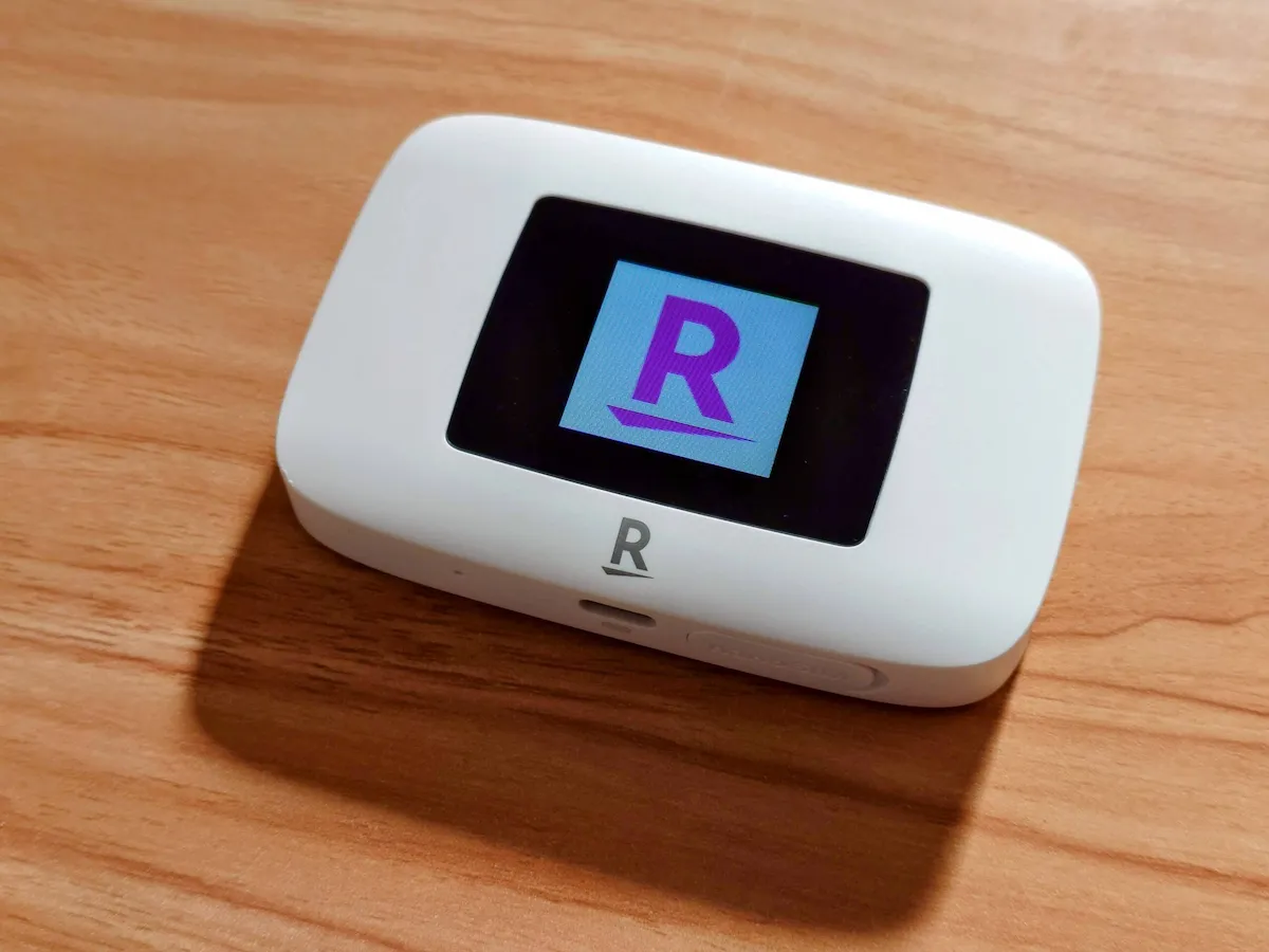 木目テーブルに置いたRakuten WiFi Pocket Platinumの液晶に楽天ロゴが表示されている様子